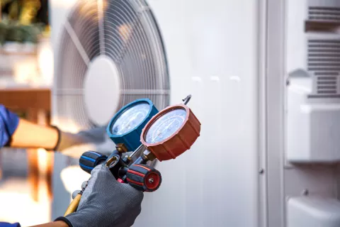 Installateur prüft das Kältemittel in der Wärmepumpenheizung mit Messgeräten.